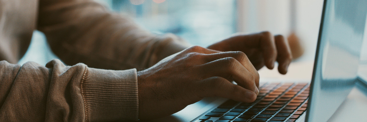 A pair of man's hands using a laptop