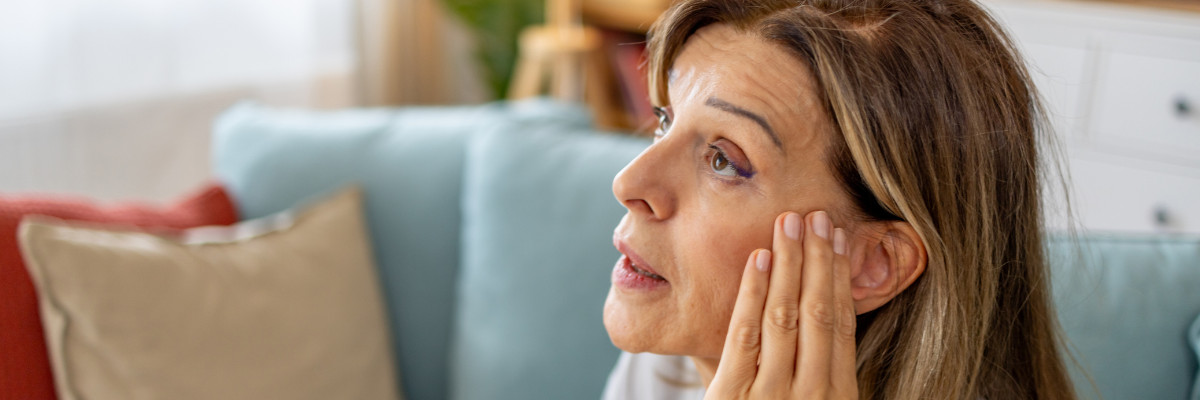 A woman rubbing her temple due to ear pain