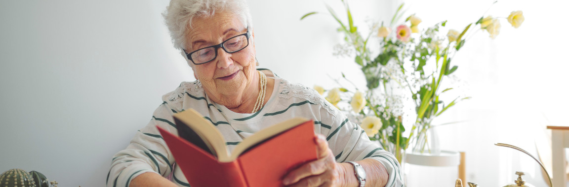 A senior reading alone in a brightly lit room